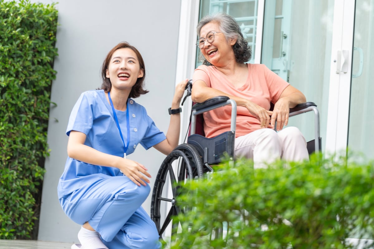 A female caregiver offering patient, one-to-one support to a senior woman at home